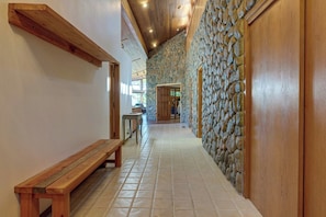 A hallway with a stone wall, wooden bench, and a door leading to another room. - Rogue Keystone Lodge/Epic River Views/Sleeps 7/SPA (Gold Beach)