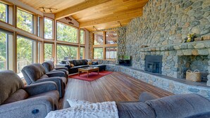 Un salón espacioso con chimenea de piedra, ventanas amplias y una zona de estar acogedora.
