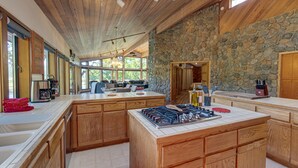 Una cocina amplia con armarios de madera, una isla central y una pared de acento de piedra.