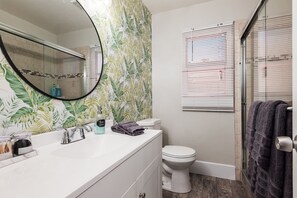 A bathroom with a white sink, a mirror, a toilet, and a shower area. - 4bd & Sleeps up to 10 - Saltwater Pool, Sunloungers, Mini Golf & Game Room (Indio)