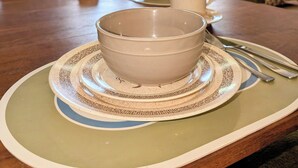 A dining table with a bowl and cups, a window with curtains, and a wall with bird decorations. - Cozy 1960s A- Frame with Mountain Views (Bodfish)
