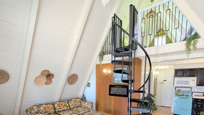 A spacious loft with a high ceiling, a wooden floor, a sofa, a coffee table, and a spiral staircase leading to an upper level. - Cozy 1960s A- Frame with Mountain Views (Bodfish)