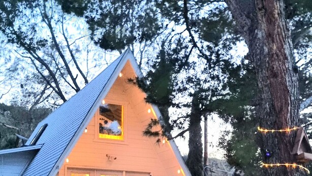 A cozy, triangular-shaped cabin with a chimney, surrounded by trees and a picnic table. - Cozy 1960s A- Frame with Mountain Views (Bodfish)