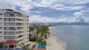 A coastal hotel with multiple balconies, a pool, and a beach view.