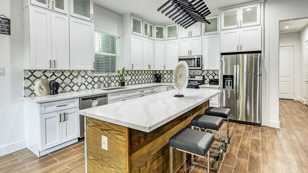 A modern kitchen with white cabinetry, a large island with bar stools, a stainless steel refrigerator, and a patterned backsplash. - "Stunning Home New Listing in the shadows of Downtown Houston A must SEE" (Houston)
