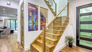 A staircase with wooden steps and glass railings, leading to a room with a cityscape poster and a dining area with a table and chairs. - "Stunning Home New Listing in the shadows of Downtown Houston A must SEE" (Houston)