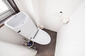 A small, white bathroom with a toilet, a hand dryer, and a paper towel dispenser. - ROADSIDE HOUSE (Sapporo)