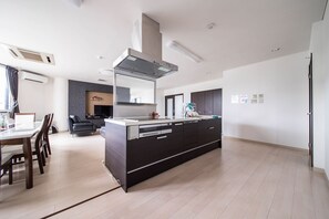 Une cuisine moderne avec des meubles de rangement aux couleurs sombres, un îlot central et un four encastré.