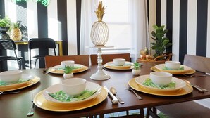 A dining table set with white bowls, gold plates, and green napkins.