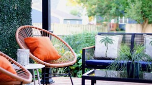 A wooden deck with wicker chairs and a sofa with patterned cushions.