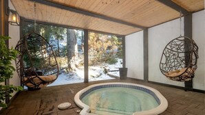 A hot tub in a wooden room with hanging chairs and a view of trees. - Whistler lodge with hot tub & cinema (Whistler)