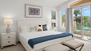 A bedroom with a large bed, two bedside tables with lamps, a blue throw blanket, and a balcony with outdoor furniture. - The Agave Cowboy | 2 Car Garage | Community Pool (Phoenix)