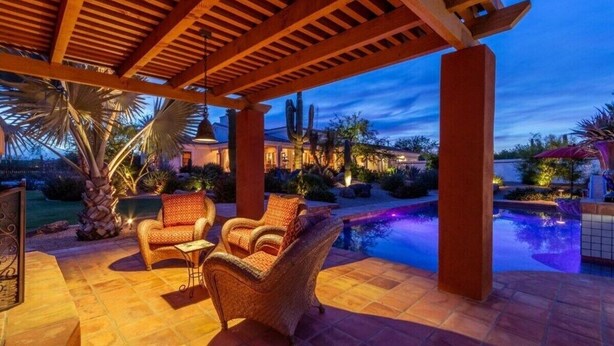 A covered outdoor area with a pool, seating, and a view of a house in the background. - Rancho Relaxo | 3 Acres + Casita + Pool (Scottsdale)