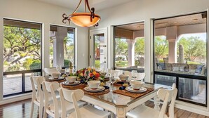 A dining area with a large table set for six, surrounded by large windows offering a view of the outdoors. - Rancho Relaxo | 3 Acres + Casita + Pool (Scottsdale)