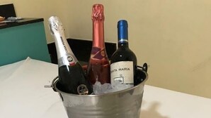 A bucket with three bottles of wine and a wine glass on a table. - hotel e motel ape goiania anel viario (Goiânia)
