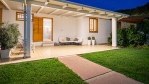 Ein modernes Haus mit überdachter Terrasse, einer Couch und Topfpflanzen.