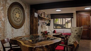 Een eetruimte met een houten tafel, stoelen en een groot decoratief wandobject.