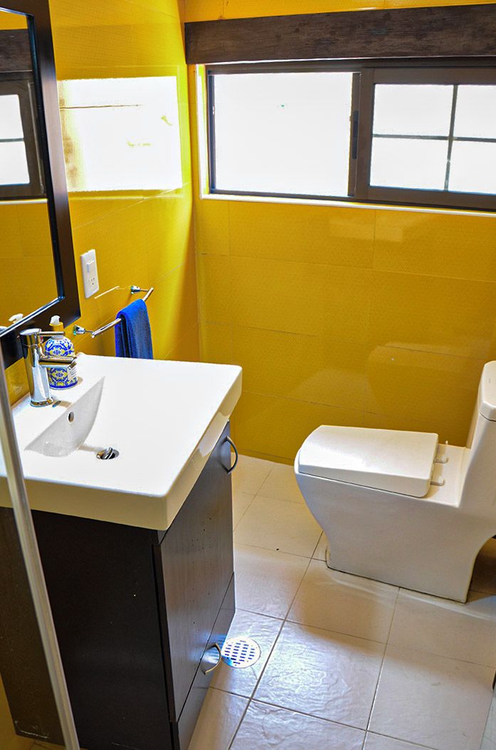 A bathroom with a white sink, a mirror, a toilet, and a window.