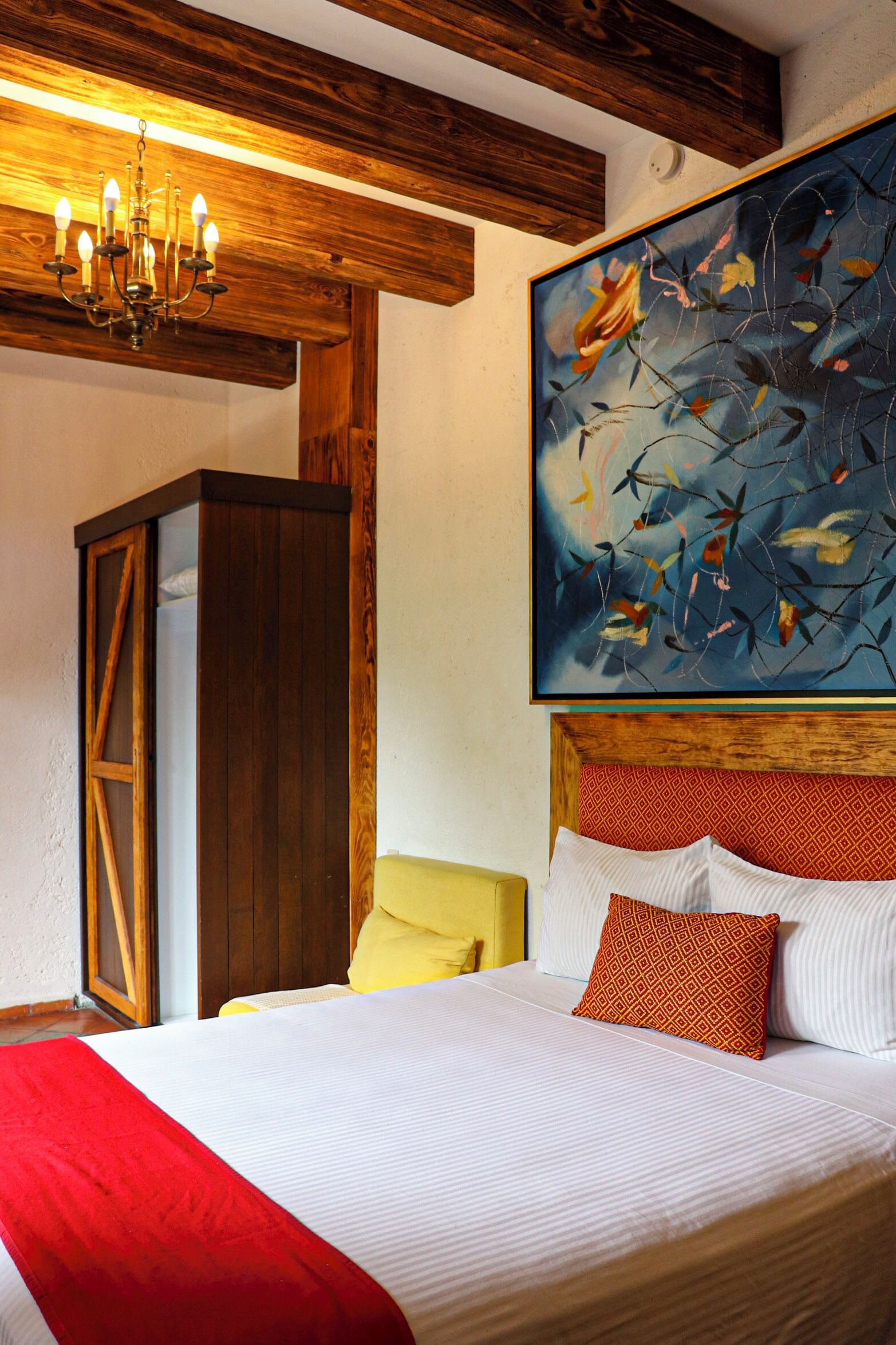 Ein Schlafzimmer mit einem großen Bett, einem Holzkopfteil, einem Gemälde und einer Kronleuchter.