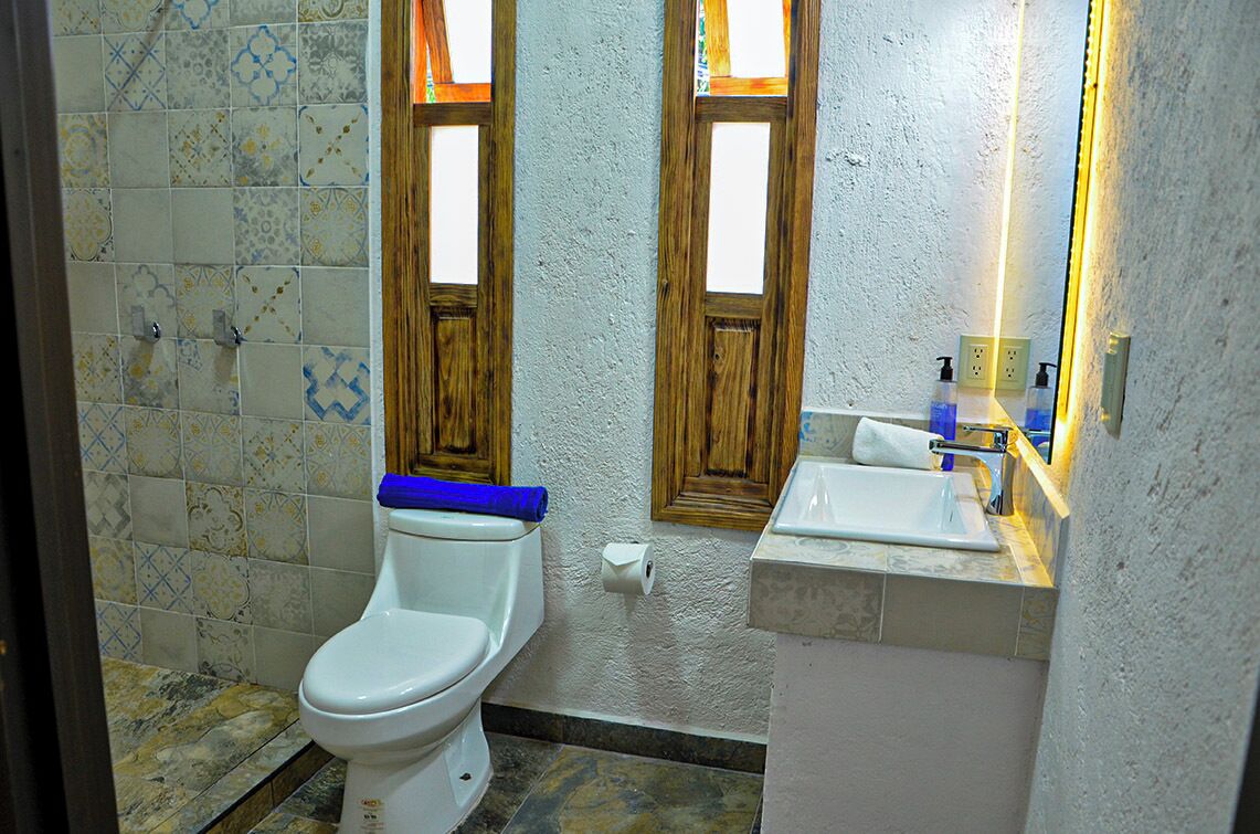Un baño con inodoro, lavamanos y espejo.
