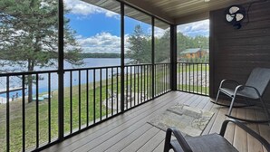 Una terraza techada con vistas a un lago, una silla y un ventilador.