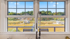 Un baño con ventana que da a un parque con un puente y un estanque.