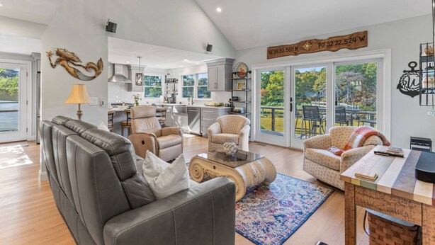 Amplia sala de estar con sofá de cuero, dos sillones, una mesa de centro y una mesa de comedor con sillas. La habitación tiene un ventanal con vistas al exterior.
