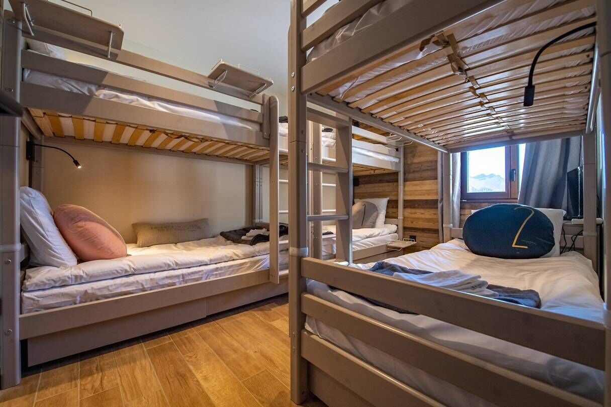 Habitació amb lliteres, parets de fusta i una finestra.