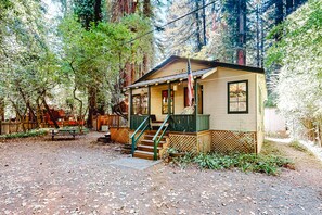Escape to a serene forest retreat with a cozy cabin featuring a porch and stairs leading to the entrance.