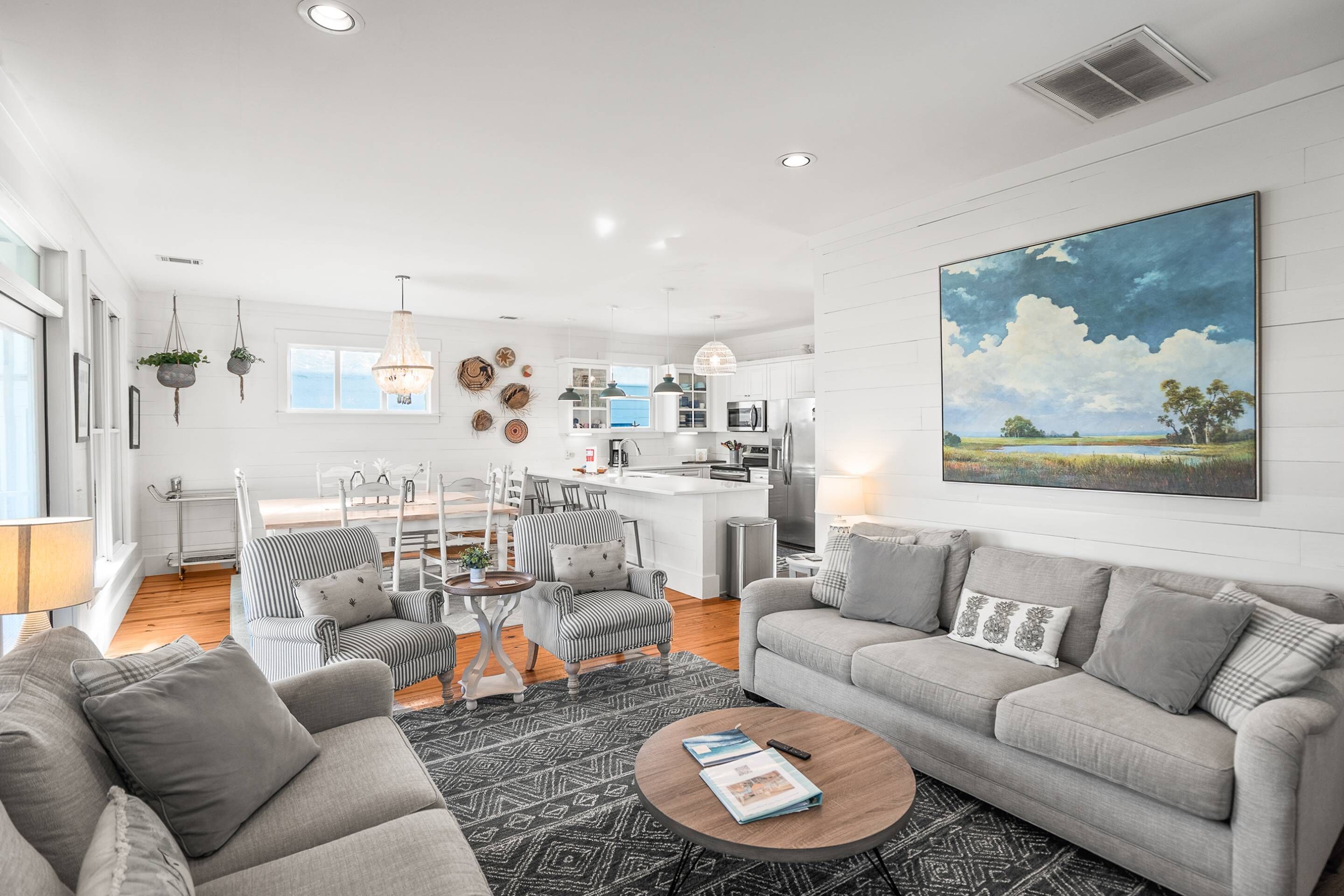 A modern living room with a grey sofa, a coffee table, and a dining area with striped chairs.