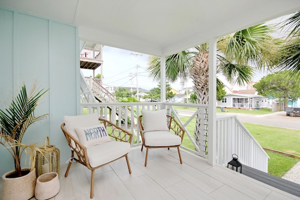 A porch with wicker chairs, a white railing, and a view of a residential street. - Sunny, dog-friendly beach house with a washer/dryer, central AC, & deck (North Myrtle Beach)