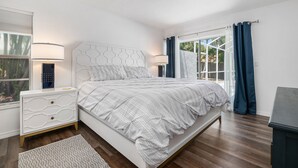A bedroom with a bed, nightstands, a lamp, a window, and curtains.