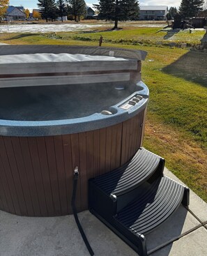 A hot tub with a wooden exterior and a metal frame, surrounded by a concrete deck.