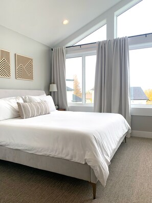 A hotel room with a large bed, a nightstand, a lamp, and a window with curtains.