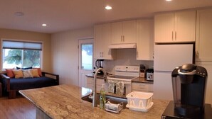 A compact living space with a bed, a sofa, a dining table, and a kitchen area. - Modern Oceanfront North Shore House, w/ AC & volleyball net, near Kualoa Ranch (Hauula)