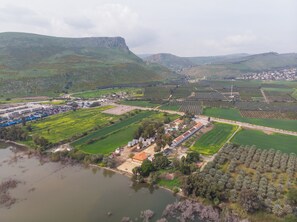 An aerial view of a coastal town with a marina, residential areas, and agricultural fields. - Selina Kinneret (Migdal)