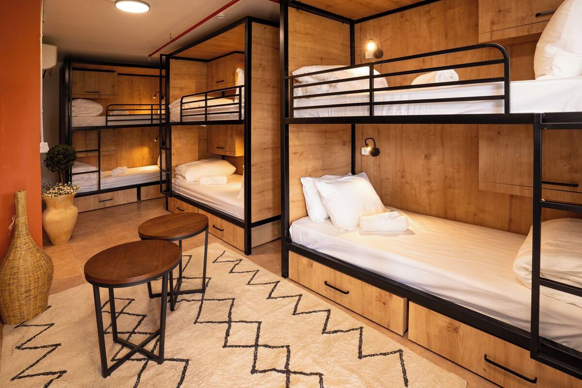 A bunk bed room with wooden walls, a small table, and a decorative vase.