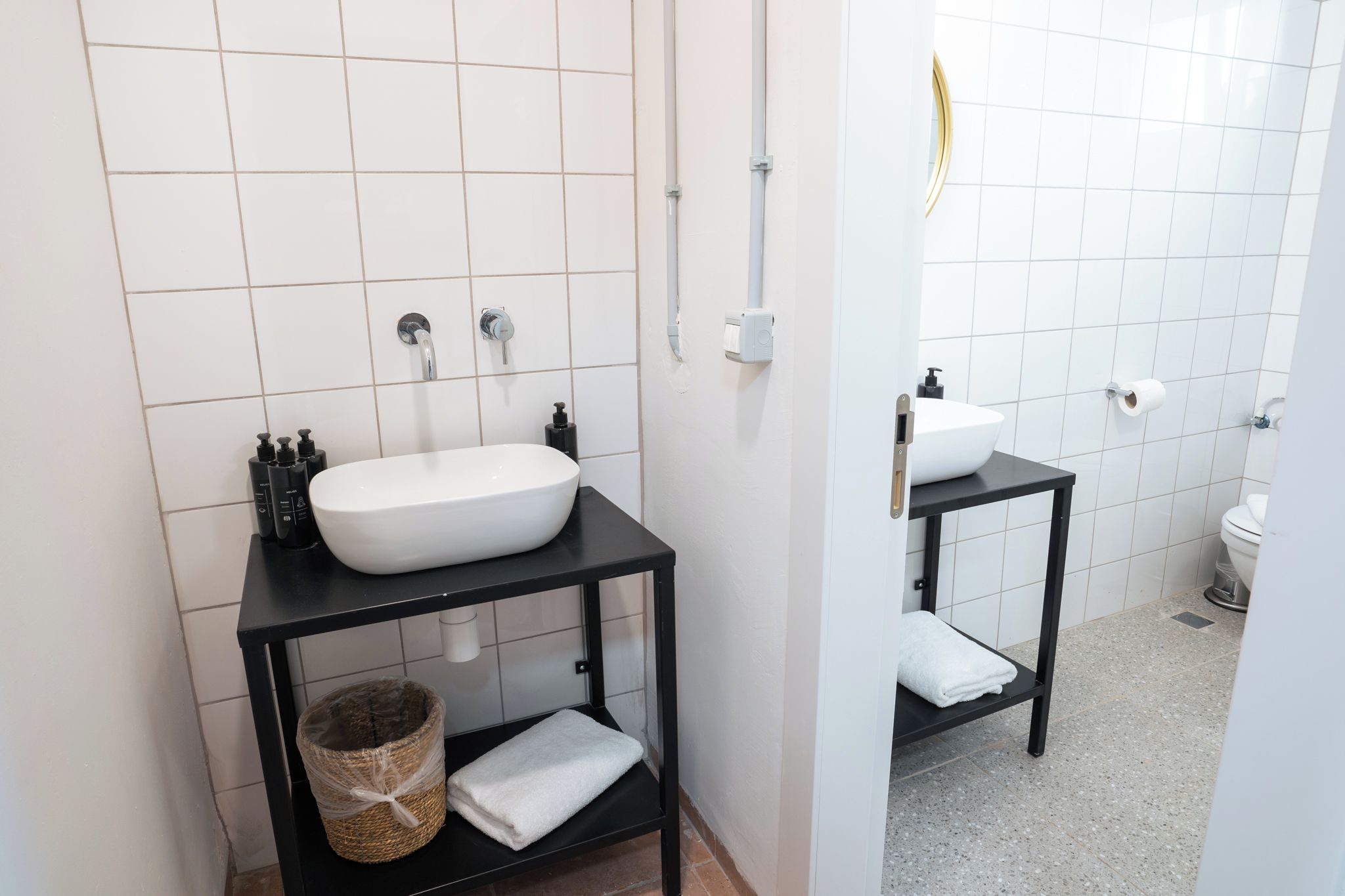 Un baño moderno con un lavamanos blanco, tocador negro y un inodoro.