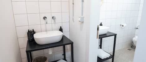 A modern bathroom with a white sink, black vanity, and a toilet.