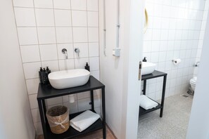 A modern bathroom with a white sink, black vanity, and a toilet. - Selina Kinneret (Migdal)