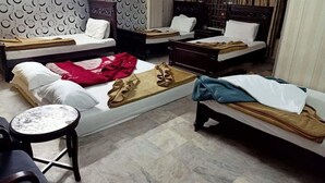 A hotel room with two beds, a small round table, and a sofa. - Hotel Al Hateem Palace (Mekhtar)