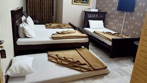 A hotel room with three single beds, each with a white pillow and a brown blanket. - Hotel Al Hateem Palace (Mekhtar)