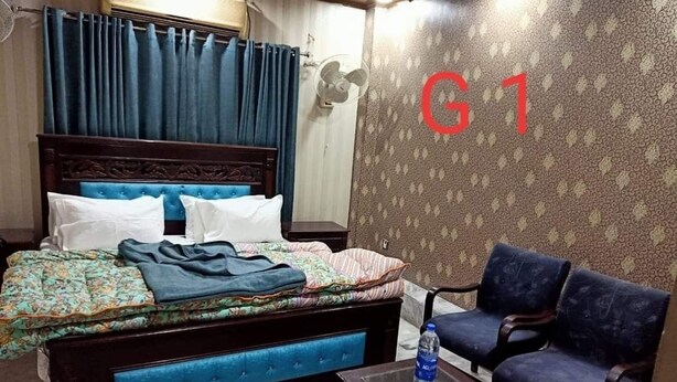 A hotel room with a bed, a sofa, a table, and a wall with a large 'G1' sign. - Hotel Al Hateem Palace (Mekhtar)