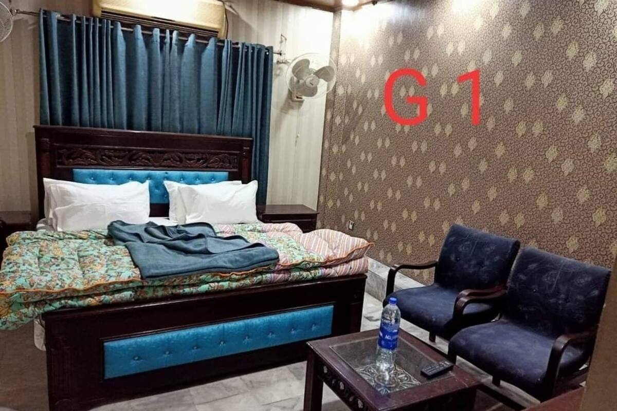 Une chambre d’hôtel avec un lit, un canapé, une table et un mur sur lequel est affiché un grand panneau indiquant « G1 ».