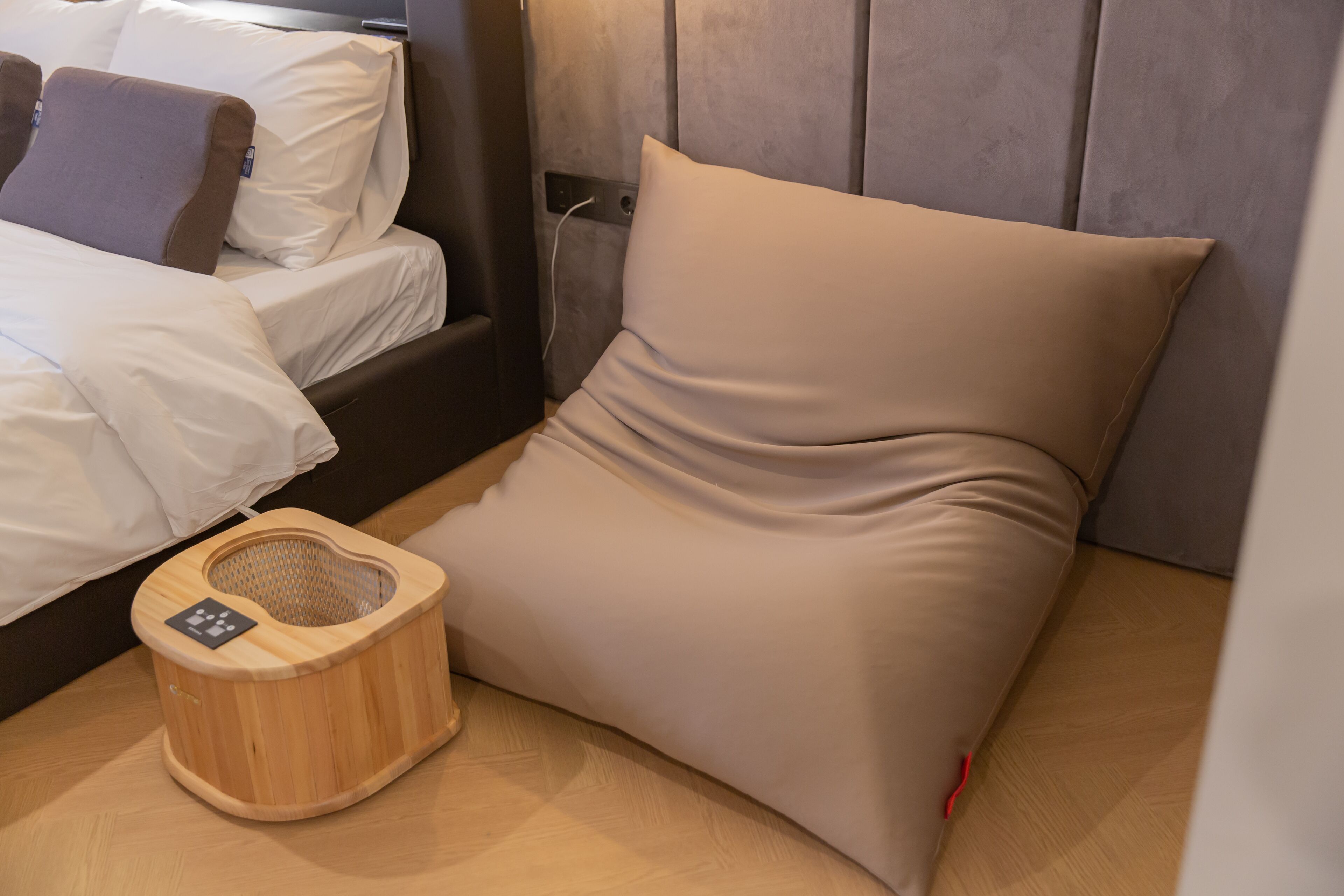 Una cama bien tendida con sábanas blancas y una mesita de noche de madera con una lámpara.