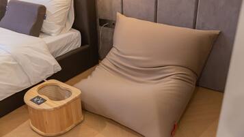 Una cama bien tendida con sábanas blancas y una mesita de noche de madera con una lámpara.