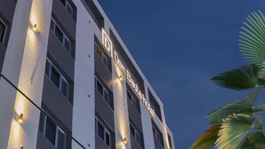 En hotelbygning med oplyst skiltning, flere etager og en klar himmel i baggrunden.