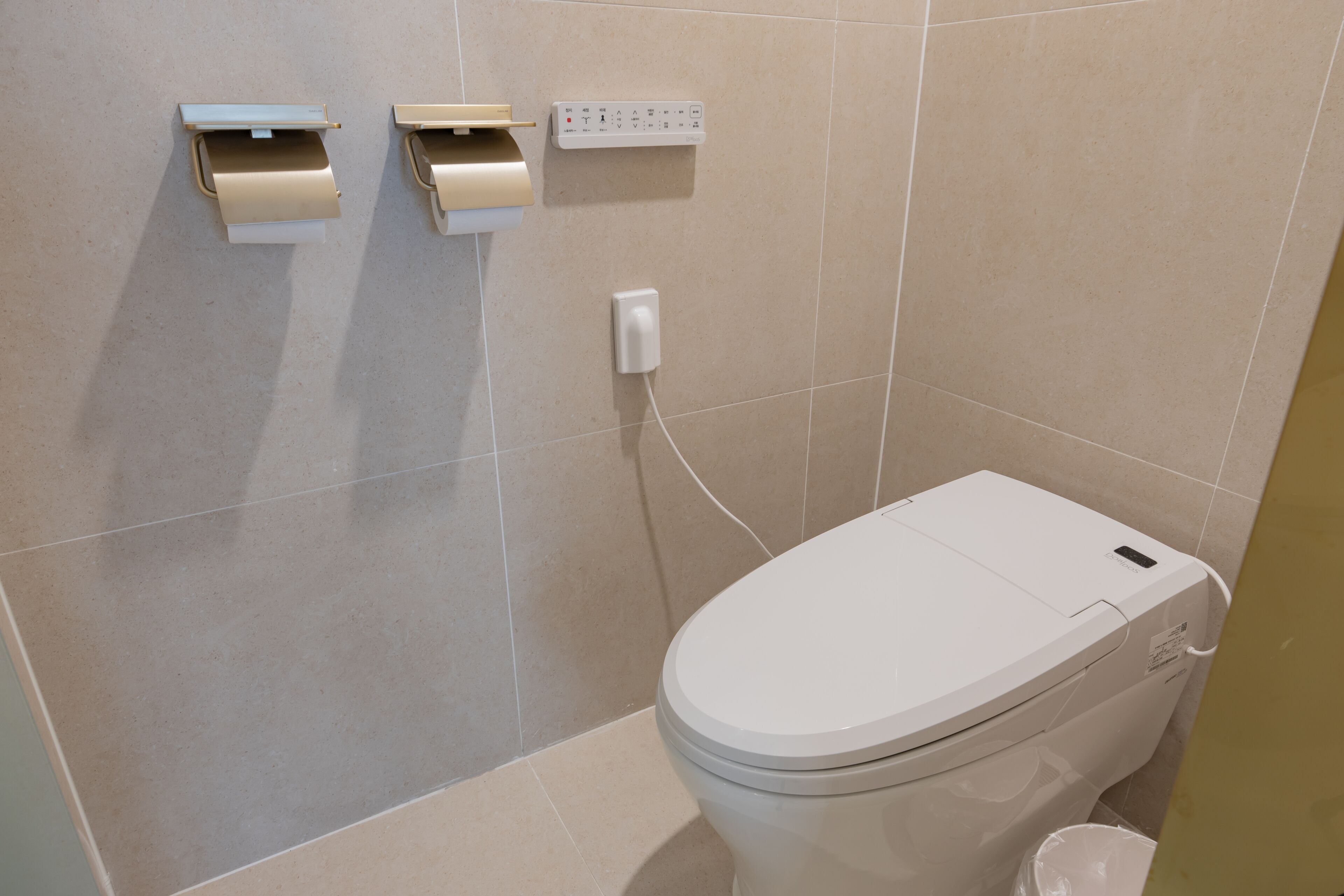 Une salle de bain moderne équipée de toilettes, d’un distributeur d’essuie-tout et d’un sèche-mains.