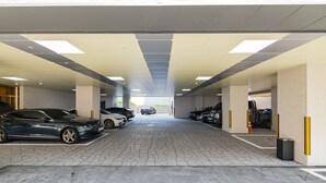 En parkeringskælder med flere biler, beton gulv og belysning.