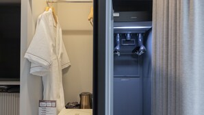 Et hotelværelse med minibar, håndklædestativ og et Samsung-køleskab.